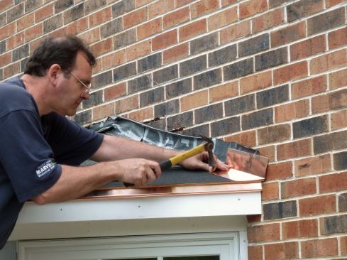 The drip edge and step flashing are attached with copper roofing nails. Note that the roofing membrane is turned up the wall underneath the flashing.