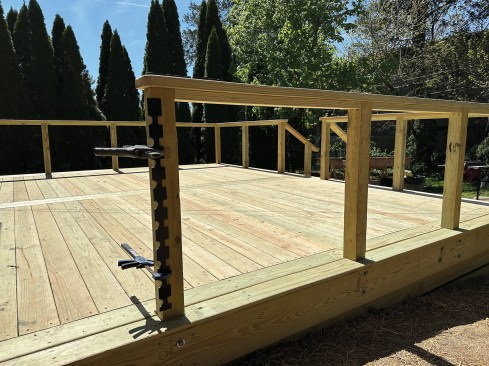 To streamline the install, he places bar clamps to hold the supplied drilling template to the posts with the bars facing away.