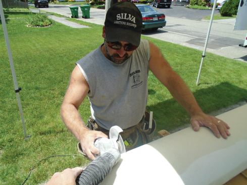 The author cuts the composite columns with a 4 1/2-inch angle grinder equipped with a diamond masonry blade. The angle grinder provides a smoother cut than a carbide blade in a circular saw, and running a shop vac while making the cut captures most of the fiberglass dust. 