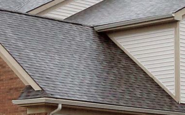 Ridge intersecting eaves. The problem with this design is that all the water that runs off the higher roof is collected into the gutter. Note that there is no downspout, so all the water that runs off the higher roof runs toward the poorly flashed ridge cap of the intersecting roof. The solution is to drop the ridge so the eaves and the gutter of the higher roof can run uninterrupted above the lower roof ridge. And, of course, pitch the upper gutter to a downspout at the corner.