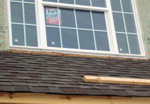 This window at right has neither sill flashing underneath the windowsill (to direct water that leaks through the window to the exterior) nor step flashing underneath the roofing shingles where it intersects the wall (to protect against splashback).
