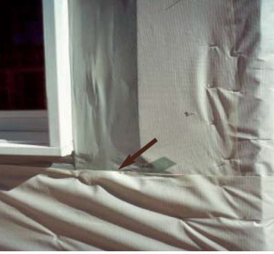 Reverse-shingled housewrap. If you follow the arrow above, you can see that the secondary moisture barrier is reversed-shingled — the bottom layer overlaps the top layer, which means that any water that gets in behind the cladding can easily be funneled into the wall rather than draining away from it. When wrapping a wall, always start at the bottom so each successive layer overlays the layer below.