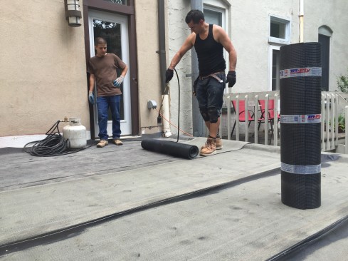 After building up the curb with two more 2x10 layers (creating a 6-inch-high curb), a roofing contractor installed tapered insulation panels to provide drainage, followed by a layer of 3/4-inch CDX plywood. Then he installed two layers of torch-down modified bitumen roofing membrane.
