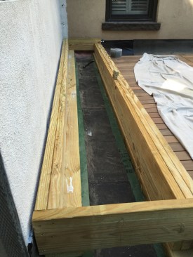 The PT base for the nearly full-width bench rests on sleepers, which are separated from the membrane roofing with strips of thick plastic.