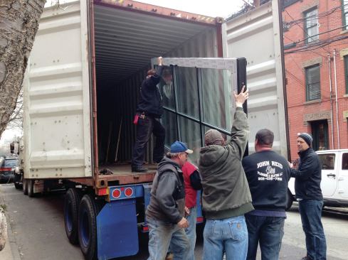 Workers unloaded the two large glazed door panels one at a time onto dollies.