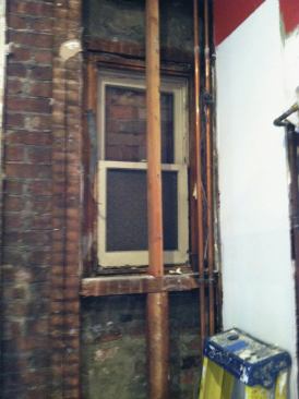 Removing the drywall revealed that previous remodelers had bricked over a window on the outside wall and left the double-hung in place on the inside.