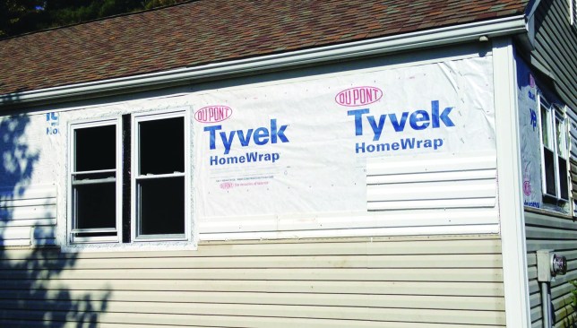 The author installed a working drainage plane using tape-sealed housewrap to keep the house walls dry, flashing below the fascia trim and pulling the roof drip edge away from the roof to direct rainwater into the gutters.