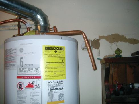 The discharge pipe must slope down, but the crimp reduces the diameter of the pipe, which is a code violation.