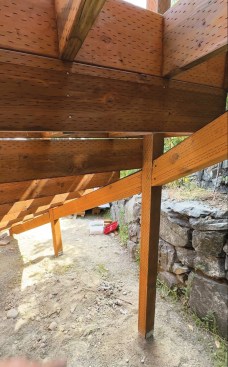 The pair of guard posts at the bottom of the stairs were fastened to the tread box with structural screws reinforced with blocking. All of the stair’s intermediate 4x4 guard posts were installed on metal post bases bolted to concrete footings, which I located and poured after the stairs were framed. Between those posts, I installed 4x6 beams to support the tread boxes, first cutting them to length and fastening them to the posts with structural screws, then installing SST LS50 skewable brackets to reinforce the post-to-beam connections. Then I locked each box to the beam with 4-inch FastenMaster TimberLok screws and flashed the tops of the beams with self-adhering flashing tape. Along the inside radius of the stairs in the center sections, I had to set the beams inside the posts instead of between them. Otherwise, the beams would have stuck out too far and disrupted the skirting detail. While the lowest beam section fit between the posts, I had to notch out the skirt rail to fit around the beam and bracket. The cuts for all the beams that support the tread boxes were complex, so I started with a template to find the angles for the cuts and help me find the finish lengths for the beams.