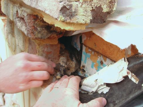 When we finally opened up the wall, we discovered that the through-wall flashing had been pieced in, with the seams simply lapped, not sealed. Water was draining off the housewrap and onto the head flashing, but it was leaking through the seams. Plus, there were no end dams, so water was spilling off each end of the flashing and finding its way past the housewrap, past a layer of foil-faced polyiso insulation, and into the wall.