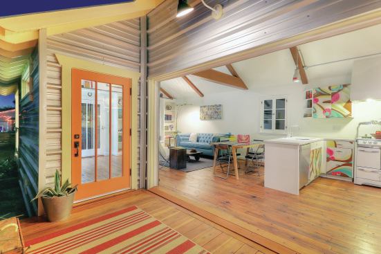 A salvaged automatic roll-up door opens the living area to a redwood deck.