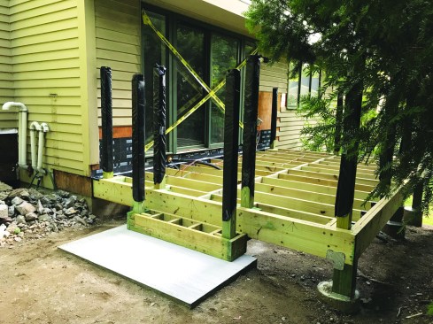 Then he wraps the posts with garbage bags, which help prevent the posts from warping and twisting by protecting them from exposure to moisture and UV rays. Taping the bags tightly around the posts helps them to last until it’s time to finish the railing system.