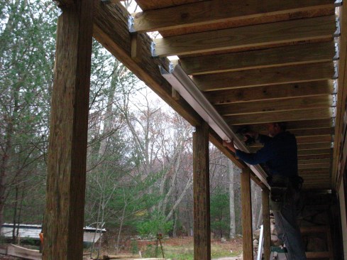 Water from the under-deck drain system is collected by a standard “K”-style aluminum gutter. When installing a system, the author typically oversizes the rim joist to accommodate the gutter.