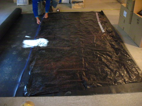 Using a piece of black plastic (an old tarp could also be used), the author makes a template for the membrane.