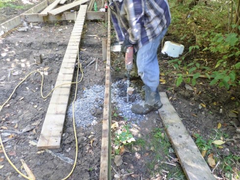 An impact driver is used to screw the auger into the ground. Then the cap plate is slipped over the auger and bolted down tight so that it rests firmly on the layer of crushed stone. Finally, the post bracket is threaded onto the assembly.