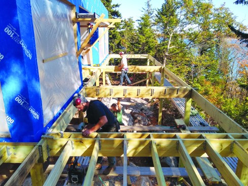 Deck framing continues down the side of the building and around the corner to the rear, facing the ocean.