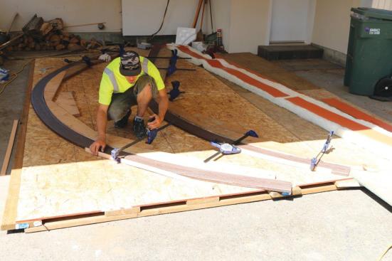 Special heating blankets make synthetic decking hot enough—around 220°F—to be pliable; here, Jeff Blotsky of Artistic Decks molds the hot decking around wooden forms cut to the radius of the desired curve and screwed to a flat plywood table.