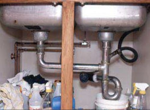 A typical kitchen sink drain assembly, with its leak-prone slip fittings, leaves a lot to be desired. This two-sink setup has no less than six slip connections.