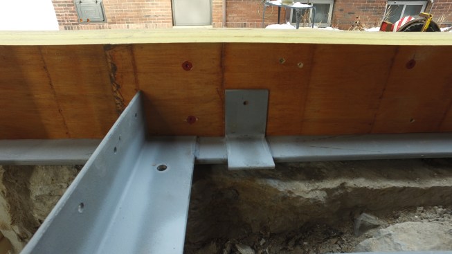 The spreaders between the foundation rails act as a joist bracket. The large hole in the bottom of the bracket holds a foundation J-bolt. In addition, smaller  L-brackets are used to secure the new rim.