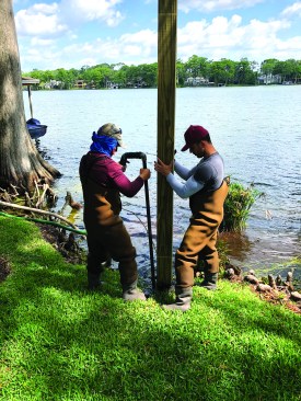 A water jet is used to set 6x6 PT pilings into the lake bottom.