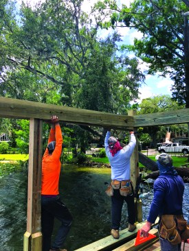 To create the box beams that support the roof, the crew fastens 2x10s to the inner and outer faces of the pilings, then fills the gap between the 2x10s with a 2x6 filler, making a convenient wiring chase.