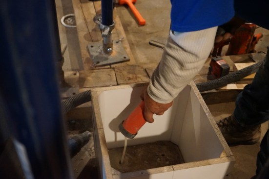 A vacuum, a wire brush, and a blow-out pump are used to clean the holes before the pins are set with epoxy.