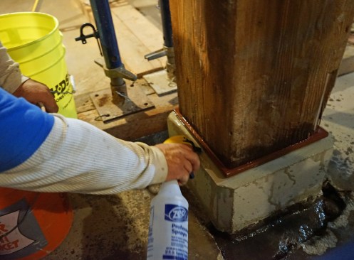 Prior to applying a non-shrinking grout, the crew sprays the pier and plate with water.