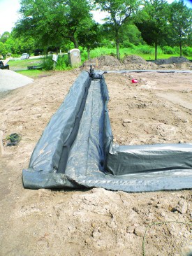 For the footing, a trench is lined with drainable geotextile filter fabric, filled with crushed stone, and roughly leveled. 