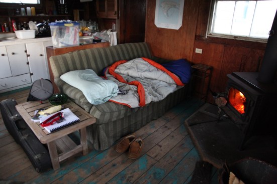 An abrupt change in the weather brought a cold wind that found its way through every crack in the shack. The author moved his sleeping bag to an overstuffed sofa in front of the wood stove where he could stay warmer and keep the fire going.