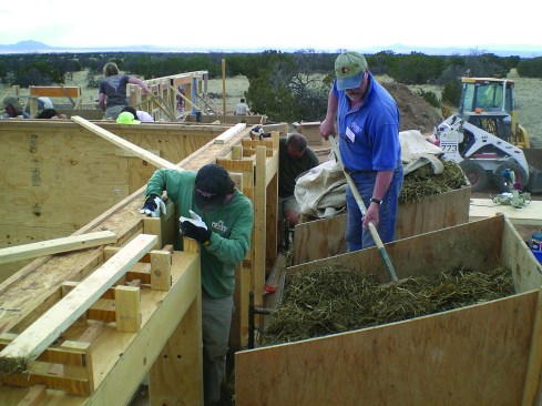 Two workers fork a mix of clay and straw into the wall-frame cavities. The mix provides a combination of insulation and thermal mass, and, says design-builder Robert LaPorte, effectively manages moisture in the wall.