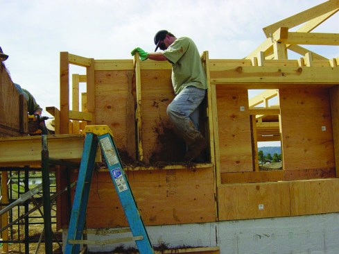 After filling the form with clay and straw, a worker tamps down the mix with his feet.