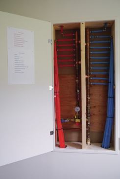 A 7-port closed-end Sioux copper manifold is concealed behind an access door. Printed sheets attached to the back of the door indicate which manifold port is connected to the various plumbing fixtures in the house. 