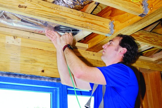 Next, Harris inserts the end of the Duct Blaster manometer’s pressure-sensing air tube into the taped-off end of the duct. When the fan is up to speed, the device’s DG-700 pressure and flow gauge will calculate the duct run’s air leakage.