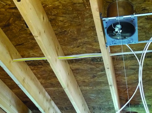 Beneath the attic floor, the 2x10 joist cavities provide a convenient service chase that easily holds recessed lighting fixtures inboard of the air barrier.