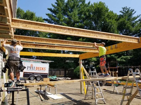 Compared with standard PT framing, I-joists are lighter, more uniformly sized, and easier to install (of course, they also require robust waterproofing if installed outdoors). The crew added web stiffeners at the hangers to take advantage of the hangers' "specifier" nail holes, which provide additional uplift resistance and help keep the beam rolling away from the joists during construction.