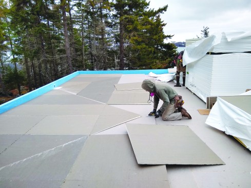 The crew builds the roof up with tapered sheets of foam, constructing valleys that lead to scupper locations in the downslope parapet wall.