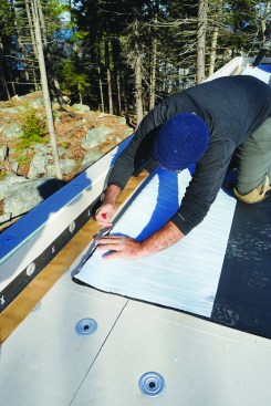 The crew slits the backing plastic on the EPDM.