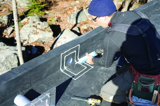 Installing a scupper involves several layers of waterproofing. First, the author applies beads of waterproofing mastic to the EPDM.