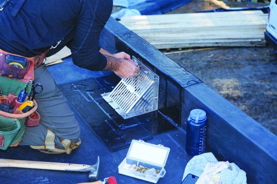 Then he applies nuts to the preinstalled studs to fasten the scupper grille in place, torquing the nuts finger-tight.
