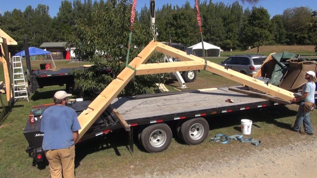 The team lifts the completed gable end rafter and collar tie assembly off the truck using the crane.