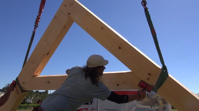 With the rafter assembly suspended from the crane, Toby applies a quick coat of linseed oil to the timbers. Applying the oil at the last minute keeps the timbers from being soiled or marked by fingerprints during transport and assembly, says Richard Krouse.