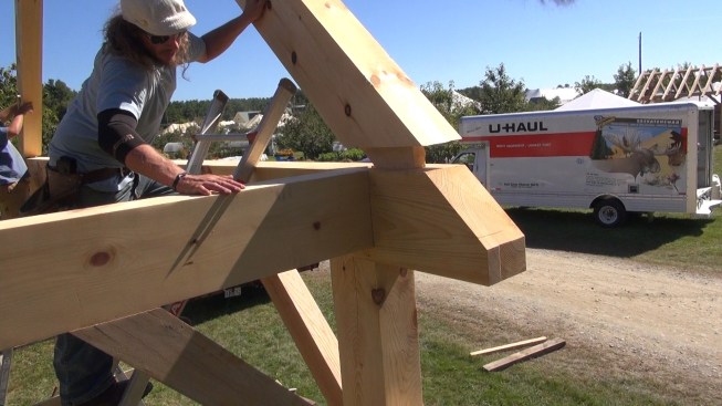 The crew gently lowers the rafter assembly into place on the wall frame.
