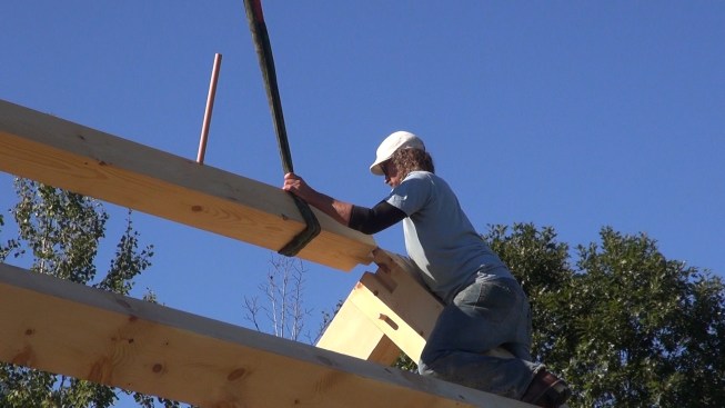 Toby guides the ridge beam tenon into its pocket at the peak of the gable end bent.