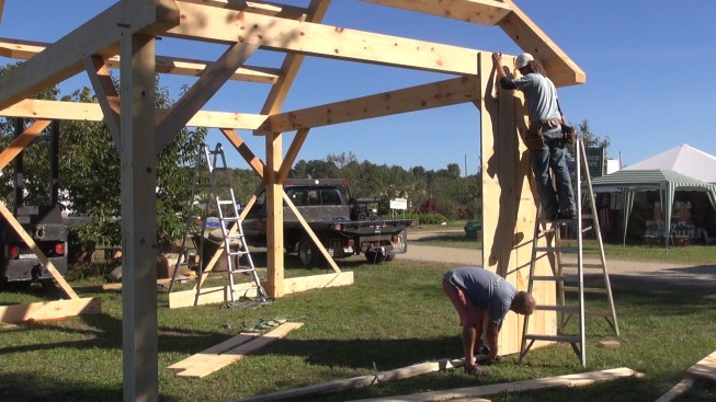 With the frame complete, the crew starts to screw rough-sawn barn-board siding onto the walls.