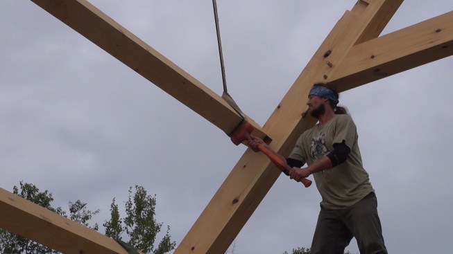 Toby pounds a purlin out of its mortise as the crew lifts the purlins off the roof frame.