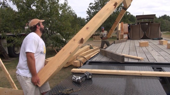 Chris and Toby guide the rafter assembly into position as the crane gently lowers the timbers onto the truck bed.