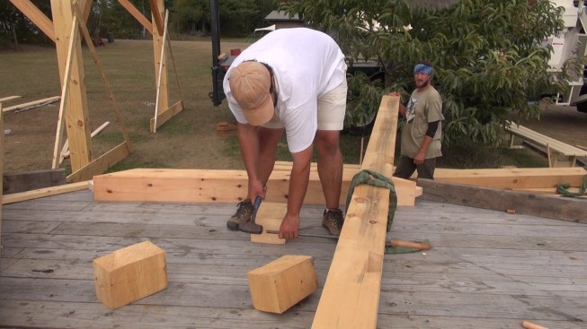 Chris drives a peg out of a timber using a steel drift pin.