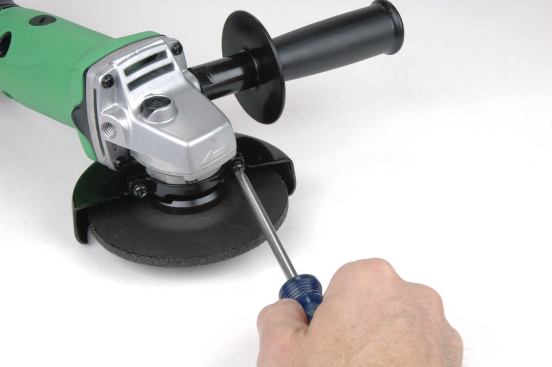 The Hitachi (shown) and Bosch grinders both require the use of a tool to adjust their guards. The Hitachi needs a Phillips screwdriver, which is not included. The Phillips-head machine screw is difficult to tighten solidly and in the rough environment at the front of an angle grinder, I think a slotted or hex head screw would be better for securing the guard. The Bosch uses a hex wrench, which stores in a rubber slot down by the battery, but leaving it there isn’t recommended because it readily falls off. By having to stop and find a tool to adjust the guards, the extra hassle makes it less likely that a needed adjustment will be made.