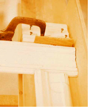 Before cutting the trim to length, the short-point markings are converted to longpoint cut lines by placing a scrap of casing and a 1/4-inch spacer between the far end of the story pole and a layout stop clamped to the extension table.