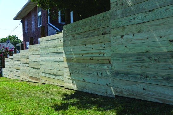 Because 2x6 PT lumber isn’t perfectly flat, it creates interesting shadow lines in the fence. For a smoother surface, vertical cleats could be screwed to the backs of the panels to pull the boards into alignment.